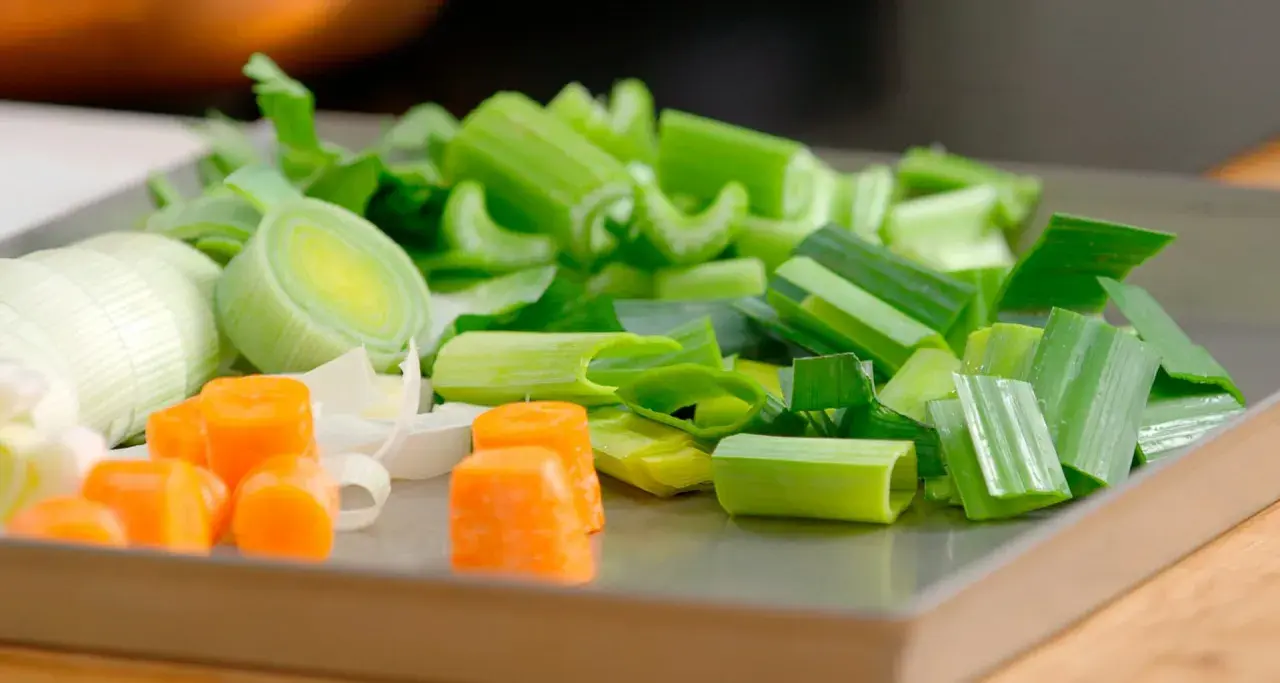 Carote, porri e sedano tagliati a pezzi, ingredienti perfetti per imparare come fare brodo vegetale.
