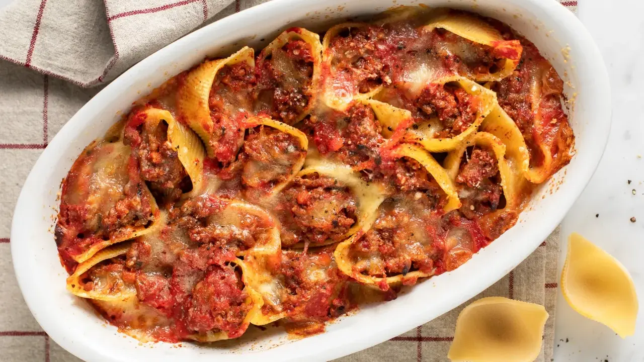 Conchiglioni ripieni al forno, un piatto invitante con pasta ripiena di carne, salsa di pomodoro e formaggio fuso, pronto per essere gustato.