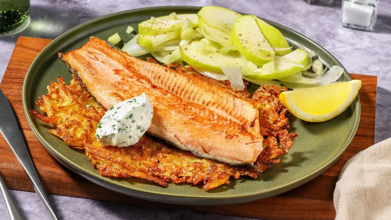 Filetto di salmone su croccanti rosti di patate, con insalata di mele e una quenelle di salsa alle erbe.