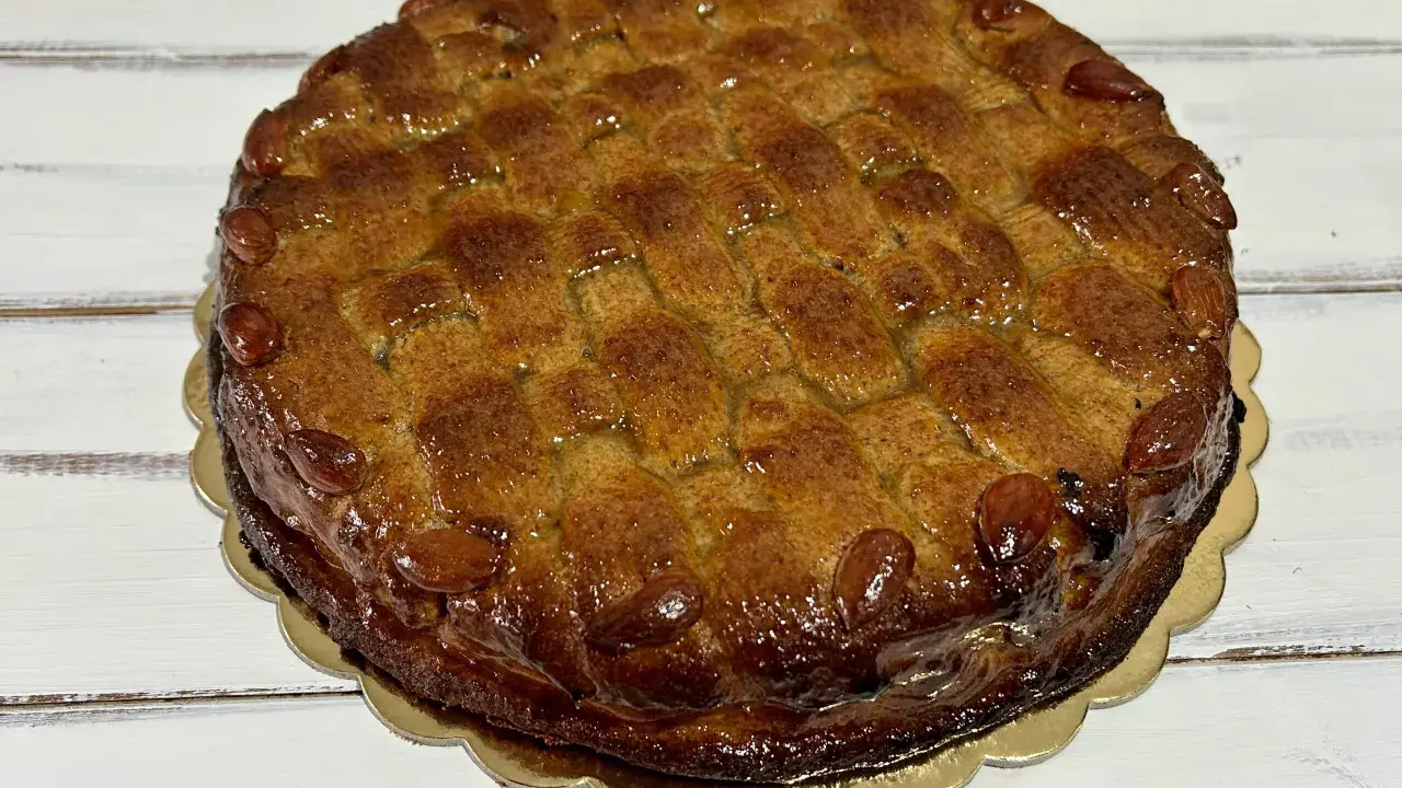 Deliziosa torta di mandorle siciliana, con una crosta dorata e mandorle intere che ne decorano il bordo.