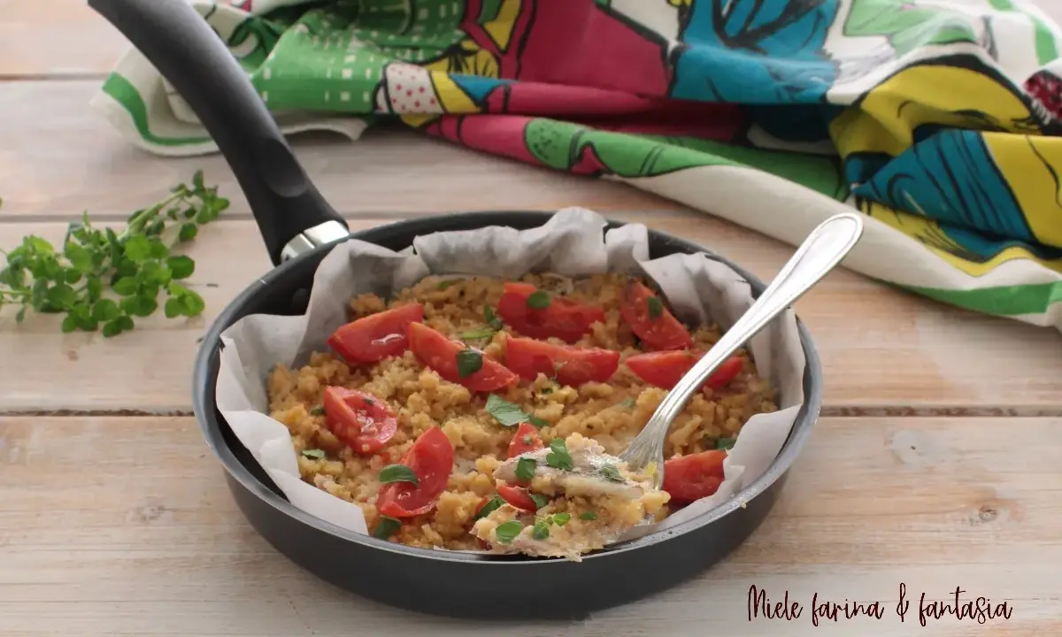 Alici gratinate in padella, un piatto semplice e gustoso con pomodorini e pangrattato, pronto per essere assaporato.