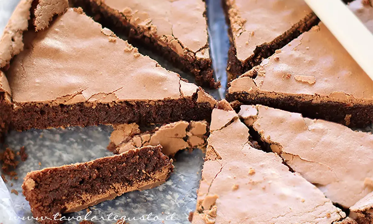 Una deliziosa torta tenerina al cioccolato, tagliata a fette triangolari, mostra la sua crosta croccante e il cuore morbido.