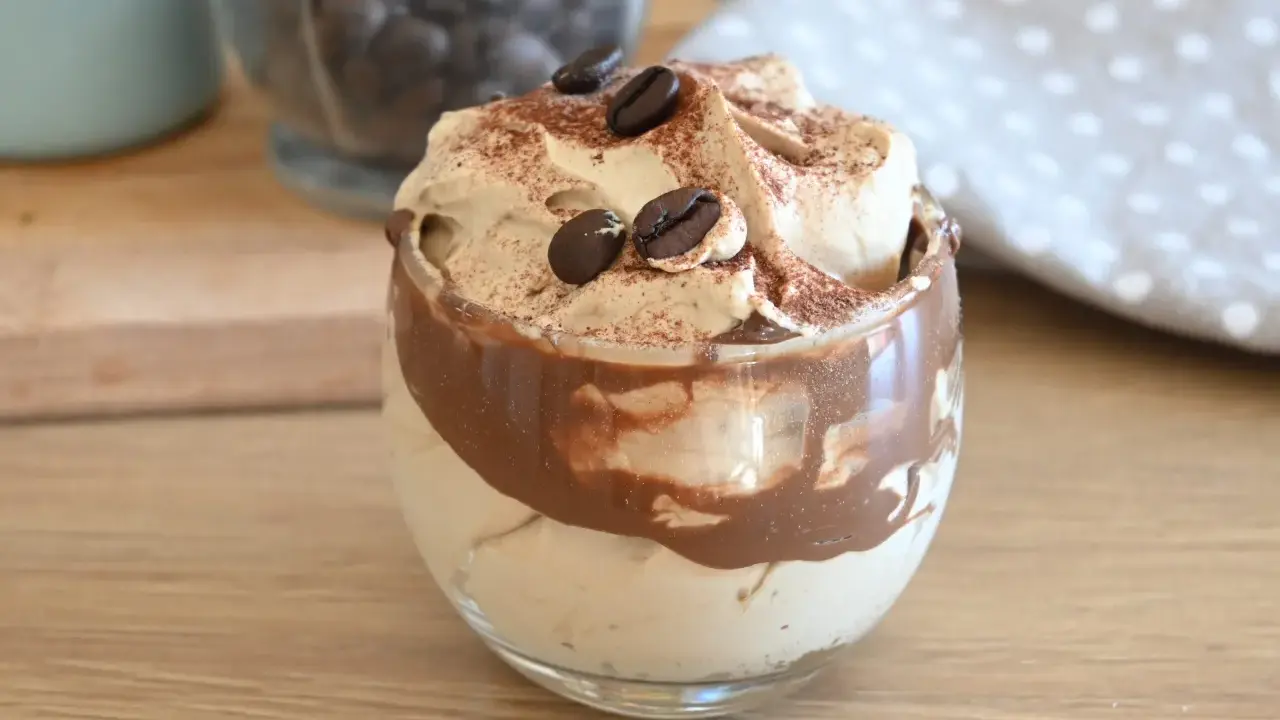 Deliziosa crema al caffè veloce in un bicchiere, guarnita con chicchi di caffè e cacao.