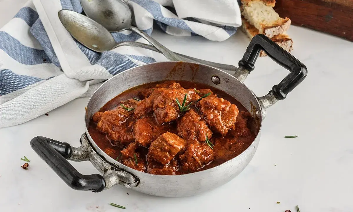 Un invitante spezzatino di vitello in umido, pronto per essere gustato. La ricetta perfetta per un pranzo domenicale.