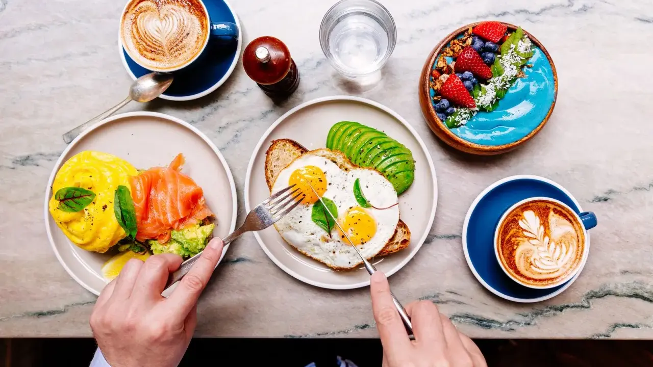 Colazione sana: uova, salmone, avocado, smoothie bowl e caffè. Ottimi esempi di colazione a basso indice glicemico per iniziare la giornata con energia.
