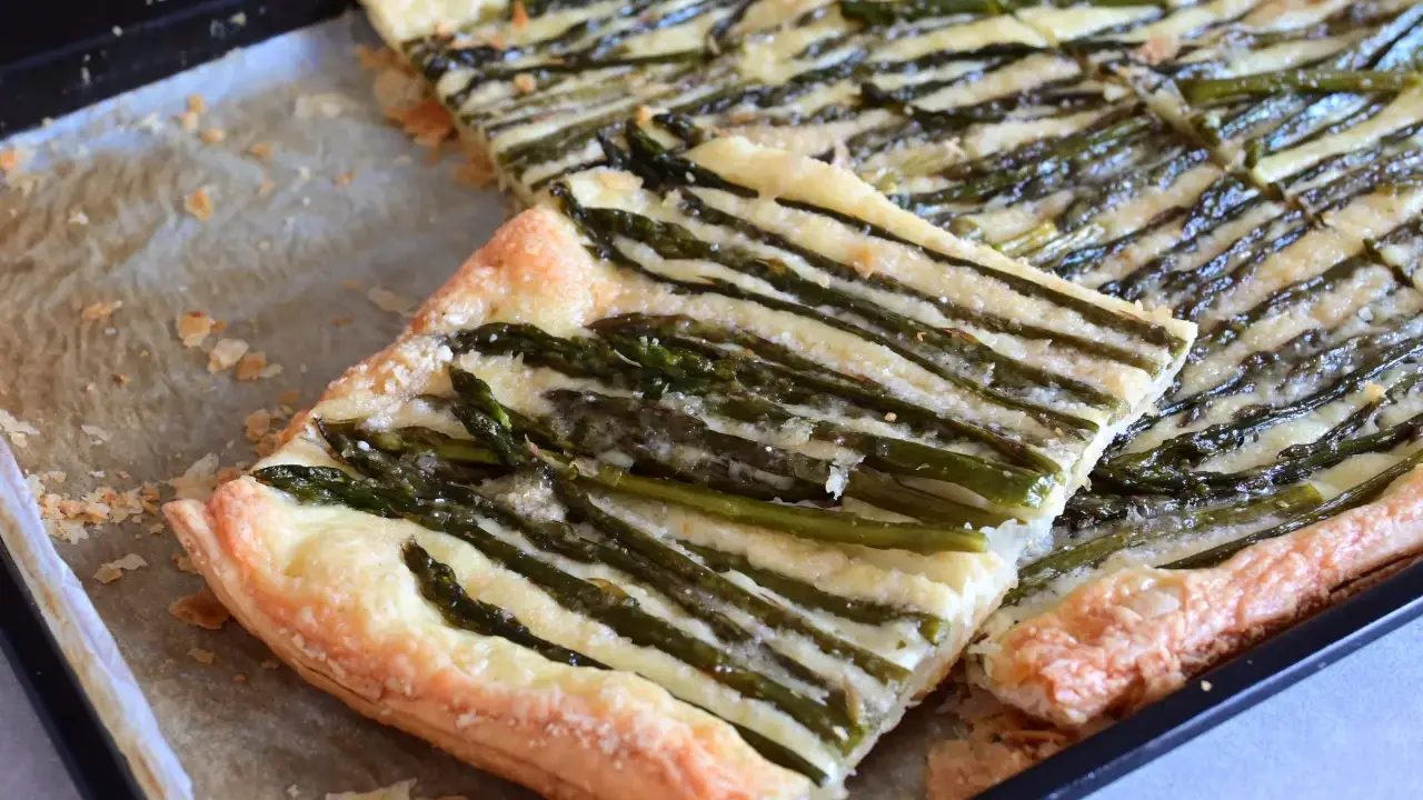 Deliziosa pasta sfoglia con asparagi e formaggio filante, appena sfornata su una teglia.