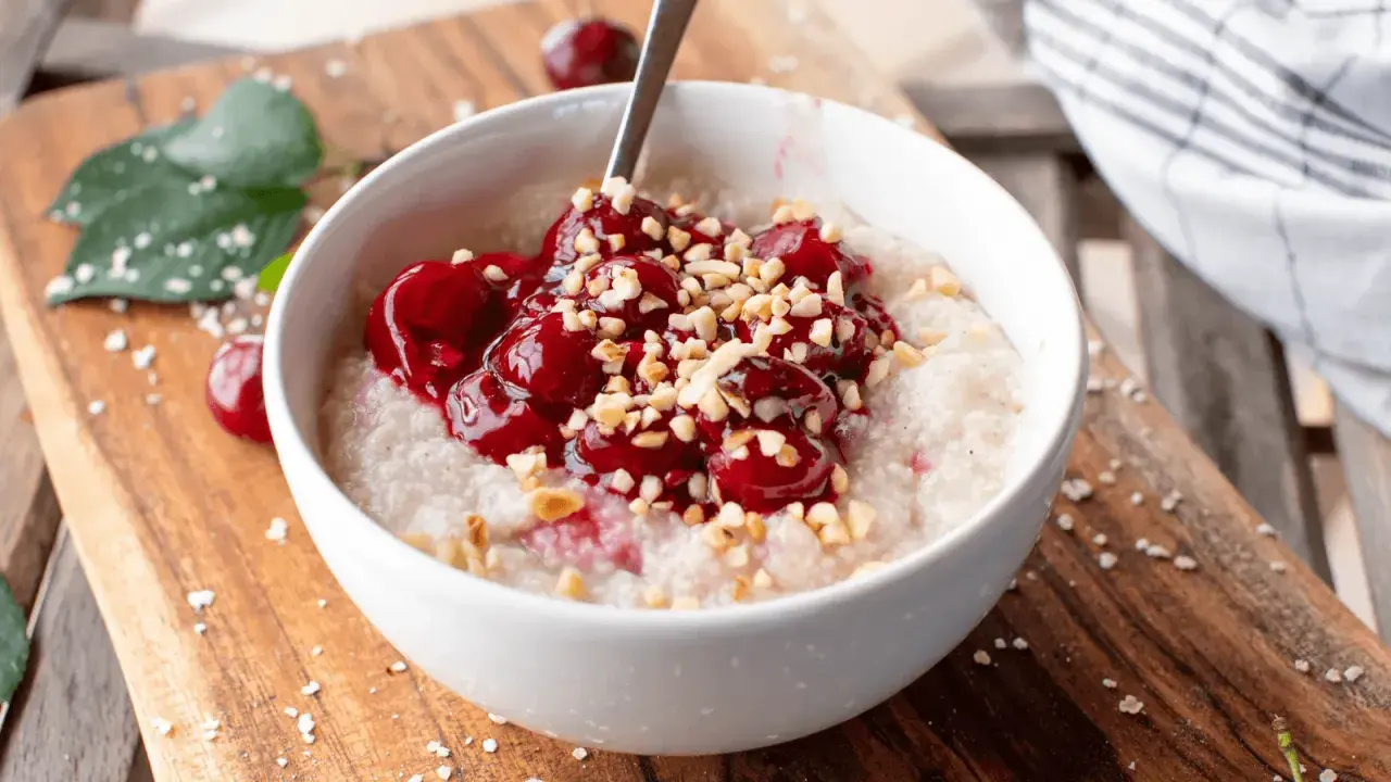 Una ciotola di porridge con ciliegie e nocciole tritate, una deliziosa colazione senza zuccheri.