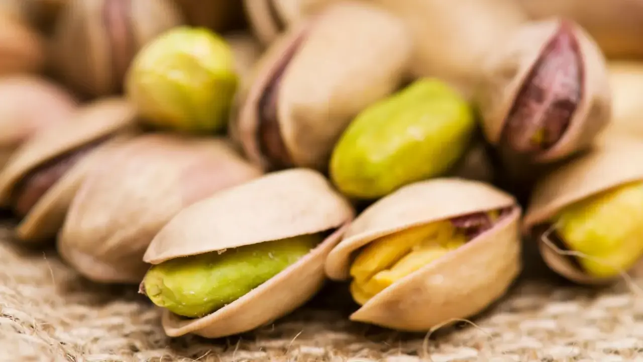 Un mucchio di pistacchi, alcuni aperti rivelano il loro interno verde e giallo. Attenzione, i pistacchi fanno ingrassare!