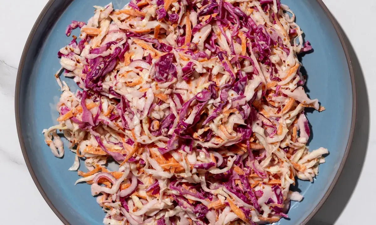 Insalata colorata con cavolo cappuccio rosso, carote e semi di senape, condita con una salsa cremosa.