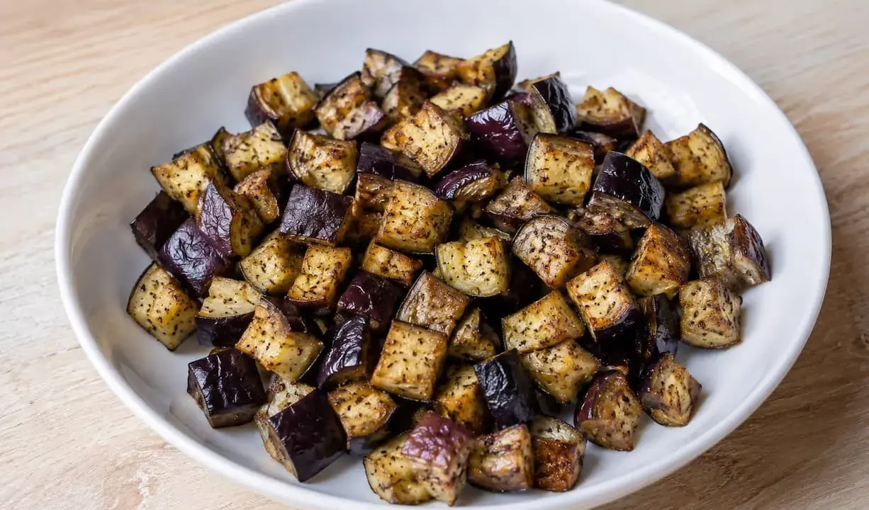 Melanzane a cubetti, cotte in friggitrice ad aria, dorate e saporite, pronte per essere gustate.