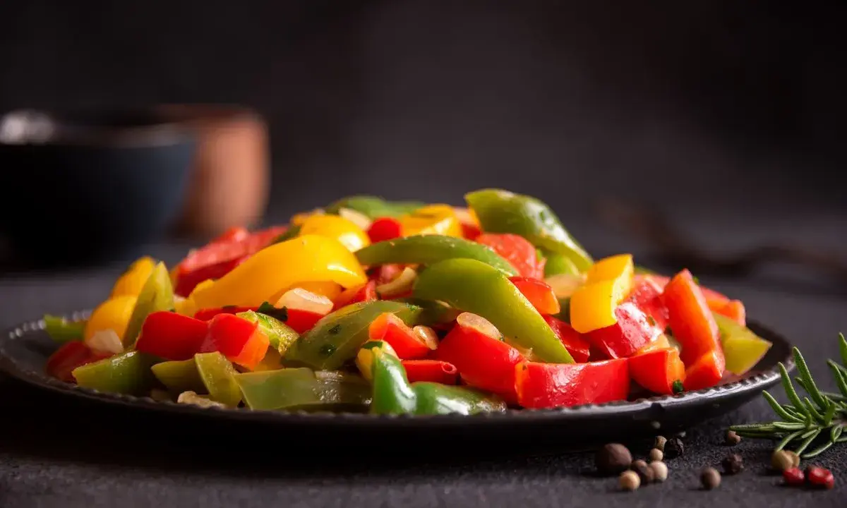 Peperoni colorati, cotti alla perfezione nella friggitrice ad aria, serviti su un piatto scuro. Un contorno sano e gustoso.