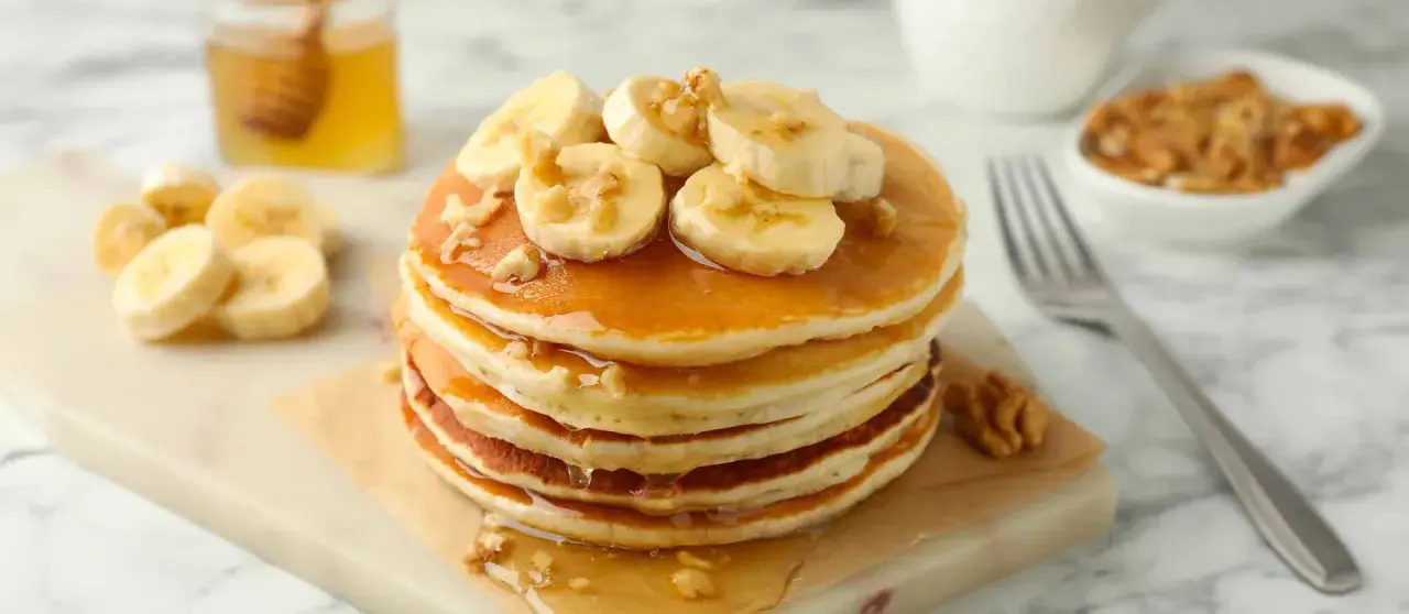 Pancakes leggeri con banane e noci, una deliziosa ricetta pancake light, guarniti con sciroppo d'acero e miele.