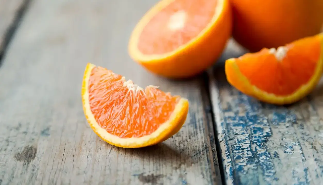 Arance fresche tagliate a spicchi su un tavolo di legno. Quante arance si possono mangiare al giorno? Dipende dal tuo fabbisogno di vitamina C.