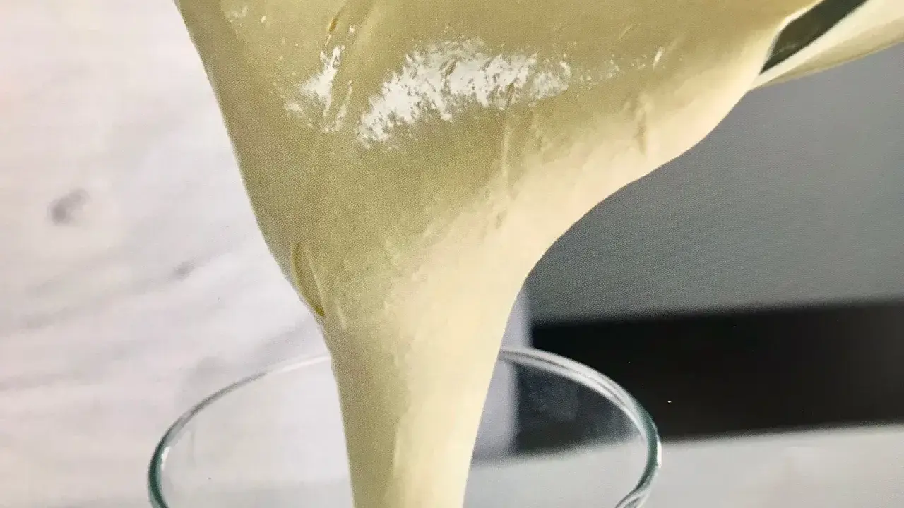 Versando una soffice pate a bombe in un bicchiere trasparente, pronta per una deliziosa preparazione.