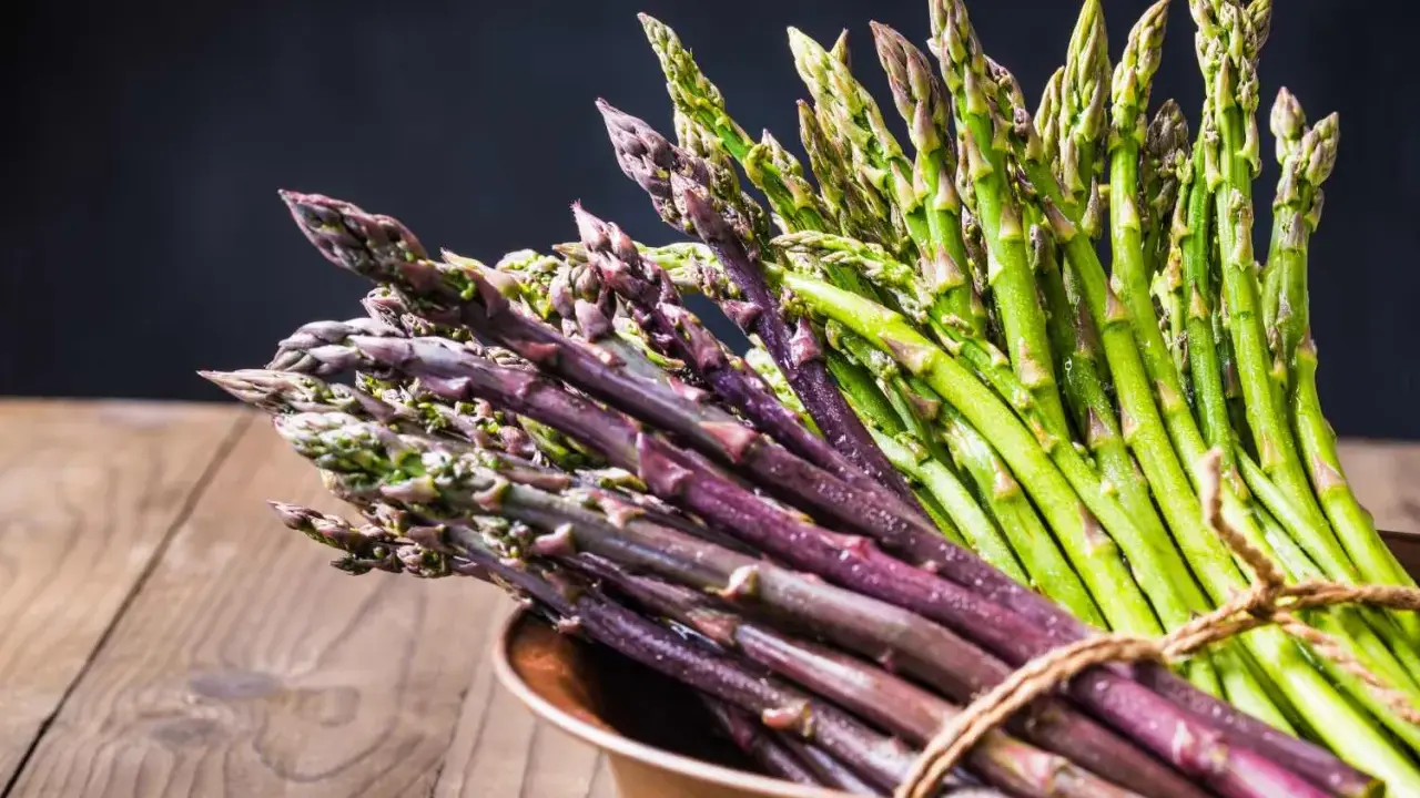 Mazzo di asparagi verdi e viola legati con spago, pronti per la cottura. Il tempo cottura asparagi varia a seconda della freschezza.