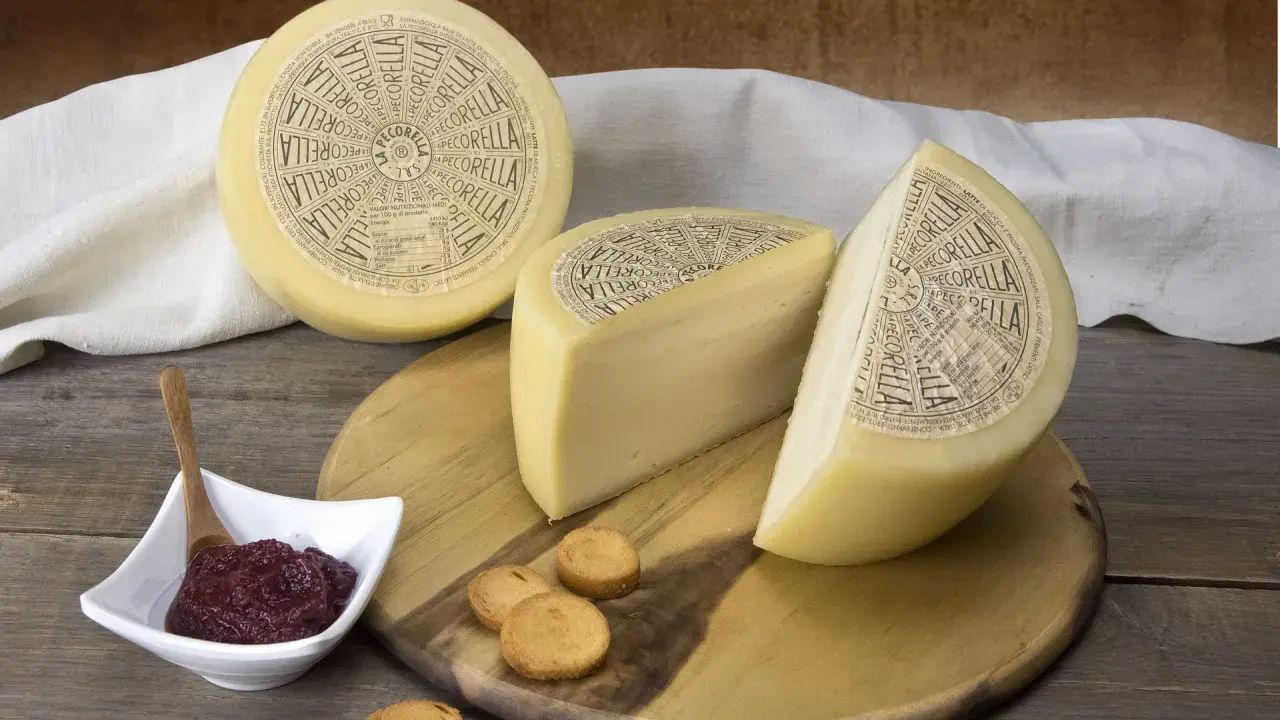 Formaggio Pecorella, un pecorino in gravidanza, servito con marmellata e taralli su un tagliere di legno.