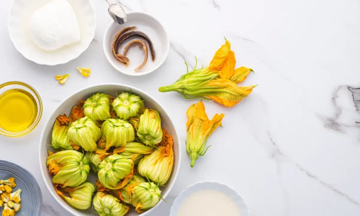 Fiori di zucca freschi, mozzarella, acciughe e olio d'oliva pronti per essere cucinati.