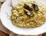 Un cremoso risotto con carciofi freschi, guarnito con prezzemolo tritato e un filo d'olio.