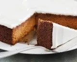 Una fetta di torta di carote e yogurt, soffice e ricoperta di glassa bianca, pronta per essere gustata.