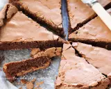 Una deliziosa torta tenerina al cioccolato, tagliata a fette triangolari, mostra la sua crosta croccante e il cuore morbido.