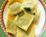 Ravioli ricotta e spinaci conditi con burro fuso e salvia, serviti su un piatto decorato.