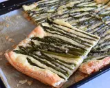 Deliziosa pasta sfoglia con asparagi e formaggio filante, appena sfornata su una teglia.