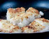 Filetti di merluzzo dorati e succulenti in padella, conditi con pepe nero.
