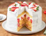 Torta fragole e panna, soffice pan di Spagna farcito con panna montata e tante fragole fresche, decorata con fragole a fette e ciuffi di panna.