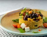 Cous cous condito con olive, ceci, pomodorini e feta. Un'idea gustosa su come condire il cous cous per un piatto colorato e saporito.