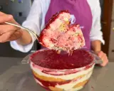 Un cucchiaio solleva una porzione generosa di un goloso tiramisù alle fragole, stratificato con crema e biscotti, pronto per essere gustato.