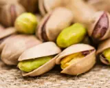 Un mucchio di pistacchi, alcuni aperti rivelano il loro interno verde e giallo. Attenzione, i pistacchi fanno ingrassare!