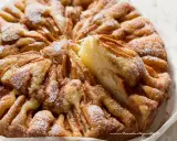 Una deliziosa torta di mele, cosparsa di zucchero a velo, con una fetta appena tolta che ne rivela la morbidezza.