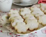 Deliziosi biscotti al burro a forma di fiore, spolverati di zucchero a velo, su un vassoio floreale.