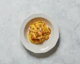 Un piatto di spaghetti alla carbonara, con il suo guanciale croccante e la crema d'uovo e pecorino, pronto per essere gustato.