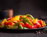 Peperoni colorati, cotti alla perfezione nella friggitrice ad aria, serviti su un piatto scuro. Un contorno sano e gustoso.