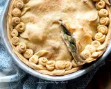Torta salata con carciofi, decorata con rose di pasta frolla e foglie, pronta per essere gustata.