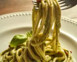 Trenette al pesto, un piatto invitante con pasta fresca avvolta in una salsa verde vibrante, guarnito con basilico.