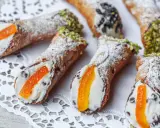 Cannoli siciliani, dolci tipici con crema e canditi, spolverati di zucchero a velo e guarniti con pistacchi o gocce di cioccolato.