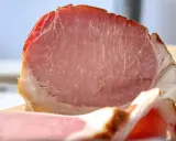 Fetta di prosciutto cotto, un insaccato rosa con striature di grasso bianco e un bordo dorato.