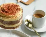 Delizioso tiramisù senza caffè, stratificato con crema e cacao, accanto a un espresso.