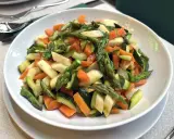 Un piatto invitante di verdure in padella: carote, zucchine e asparagi tagliati a pezzetti, cotti al punto giusto per un contorno sano e colorato.