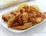 Straccetti di pollo croccanti in friggitrice ad aria, serviti con spicchi di limone.