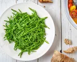 Piatto bianco colmo di asparagi di mare freschi e croccanti, pronti per essere gustati.