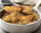 Patate in padella dorate e croccanti, condite con erbe aromatiche, servite in una ciotola bianca.