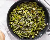 Asparagi in padella, saltati e cosparsi di parmigiano grattugiato, pronti per essere gustati.