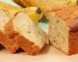 Fette di banana bread light, soffice e dorato, con banane mature sullo sfondo.