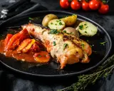 Un succulento piatto di coda di rospo cotta al forno, servita con pomodori e patate novelle.