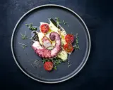 Un tentacolo di polpo alla griglia, servito su purè di patate con pomodorini confit e timo.