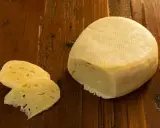 Formaggio di fossa, un sapore antico. Un pezzo di formaggio stagionato e due fette su un tavolo di legno rustico.