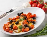 Un succulento pesce spada alla siciliana, condito con pomodorini, olive nere e capperi, guarnito con prezzemolo fresco.